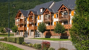 A row of chalet-style buildings with balconies, set against a mountainous backdrop.