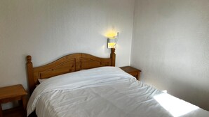 A single bed with a wooden headboard, a bedside table on each side, and a wall-mounted light fixture. - Appart à 50m des Remontées | Piscine Intérieure (Val-Cenis)