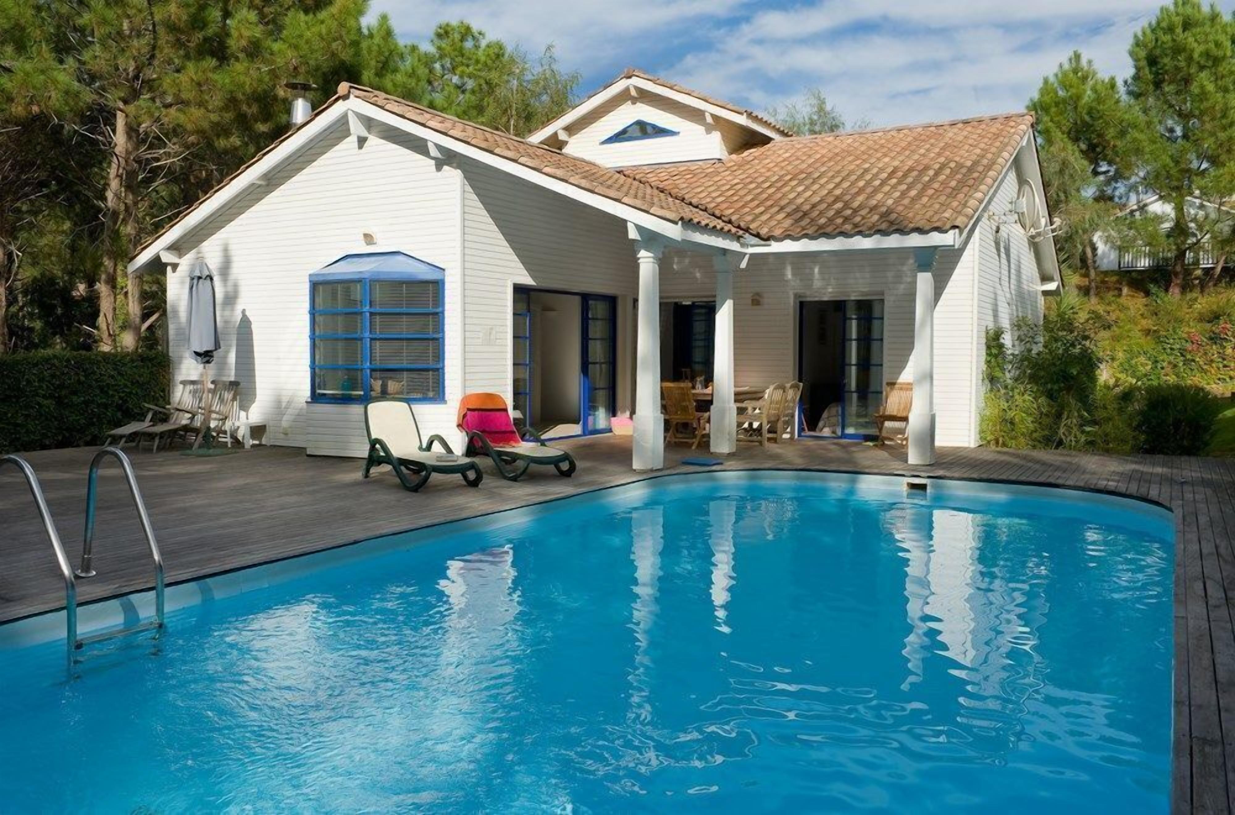 A house with a swimming pool, a covered patio, and a dining area.