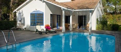 Una casa con piscina, patio coperto e zona pranzo.