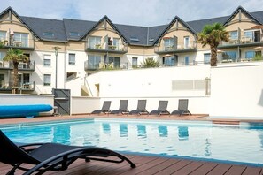 Un hôtel doté d’une piscine, de chaises longues et d’un palmier.
