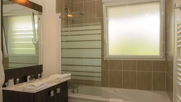 Een moderne badkamer met een badkuip, een douchecabine met glazen wanden en een wastafelmeubel met spiegel.
