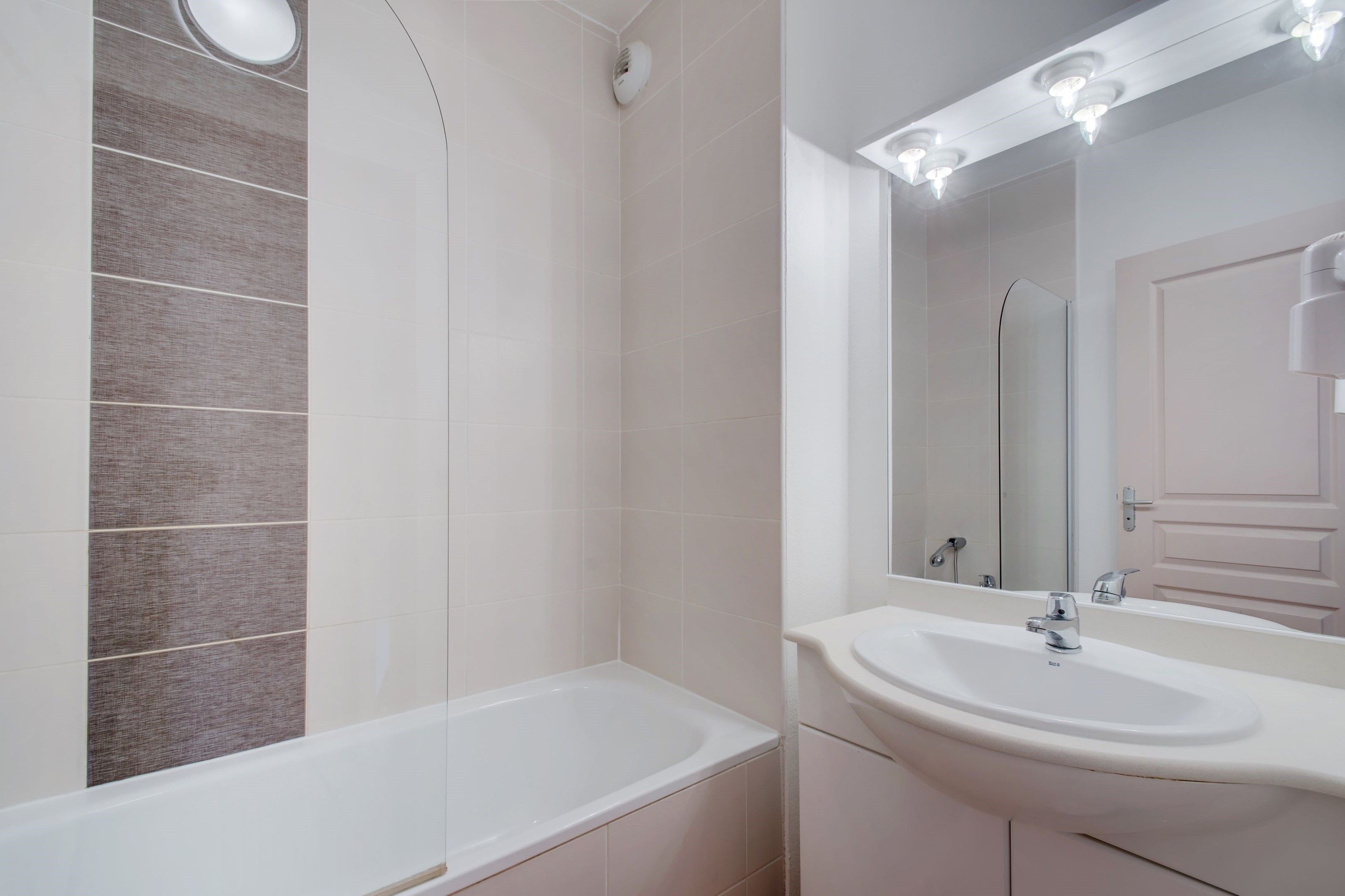 A bathroom with a bathtub, a sink, and a mirror.