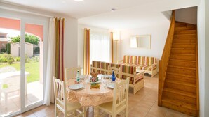 A dining area with a table set for four, a sofa, and a wooden staircase.