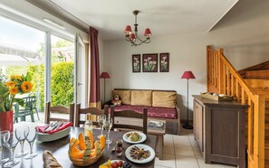 Enjoy meals in this beautifully set dining area with a wooden table, sofa, and artwork.