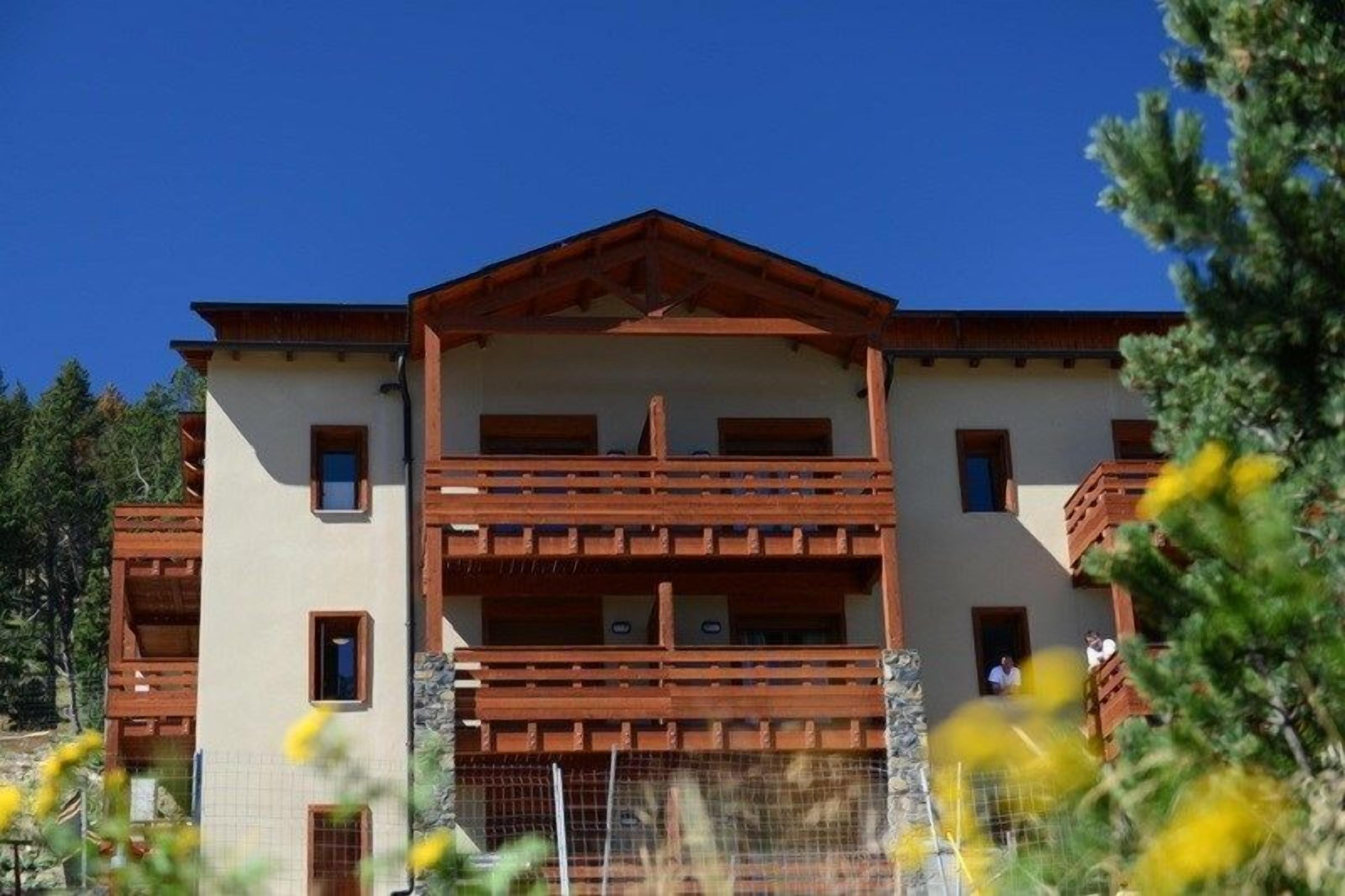A multi-story building with a symmetrical facade, wooden balconies, and a central entrance.