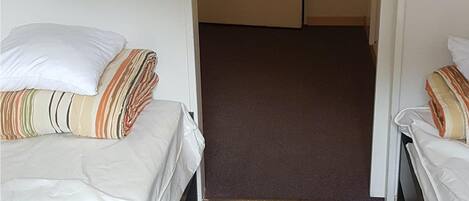 Une chambre d’hôtel avec deux lits, une porte avec une pancarte et un sol recouvert de moquette.