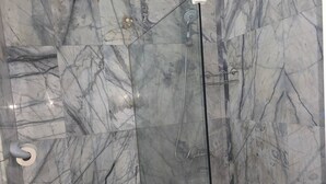 Une salle de bain avec des toilettes, une douche à parois de verre et des murs en marbre.