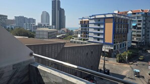 Un bâtiment moderne à la façade bleue et blanche, doté d’un panneau en bois remarquable, et offrant une vue sur le paysage urbain en arrière-plan.