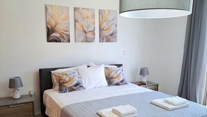 A modern bedroom with a large bed, grey bedding, and decorative wall art. - Serenity Pearl villa with a private pool,  2 min walk to the beach (Protaras)