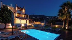 Eine moderne Villa mit Pool, Sitzgelegenheit im Freien und einer Steinmauer.