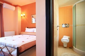 A hotel room with a bed, a bedside table, a wall-mounted air conditioner, and a bathroom with a toilet and shower. - VILLA PELAGOS VIEW,PRIVATE POOL,4 BEDROOM, 5 min from the beach! (Crete)