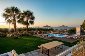 A poolside area with a wooden table, lounge chairs, and a view of the sea. - VILLA PELAGOS VIEW,PRIVATE POOL,4 BEDROOM, 5 min from the beach! (Crete)