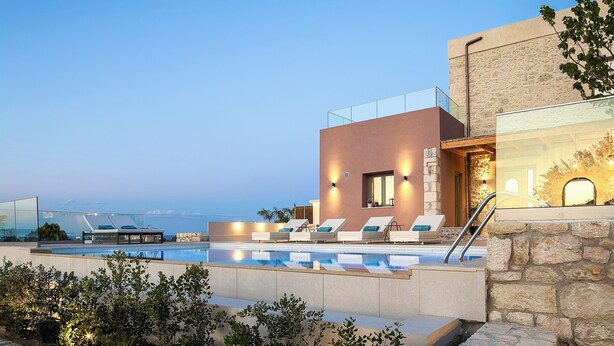 Ein moderner Poolbereich mit Liegestühlen und freiem Blick auf den Ozean.