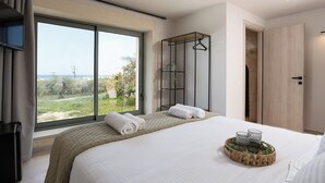 Ein modernes Hotelzimmer mit großem Fenster, einem Bett mit ordentlich gefalteten Handtüchern, einem Nachttisch mit Gläsern und einem Holzschrank.