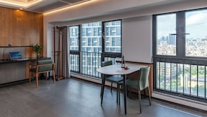Een moderne kantoorruimte met een groot raam met uitzicht over de stad, een bureau met een laptop en een eethoek met stoelen en een tafel.