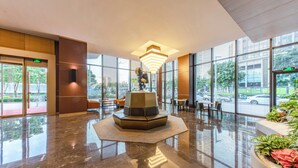 Een moderne lobby met een centraal zitgedeelte, grote ramen en een gepolijste vloer.
