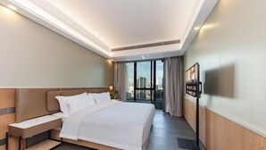 Een moderne hotelkamer met een groot bed, een nachtkastje, een televisie en uitzicht over de stad.