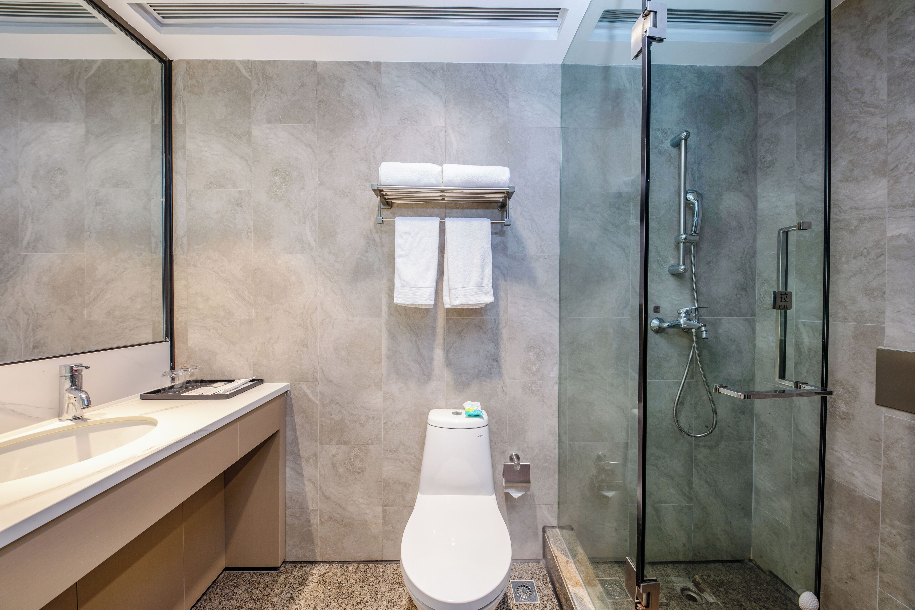 Une salle de bain moderne avec une douche à parois de verre, des toilettes et un meuble-lavabo avec un évier.
