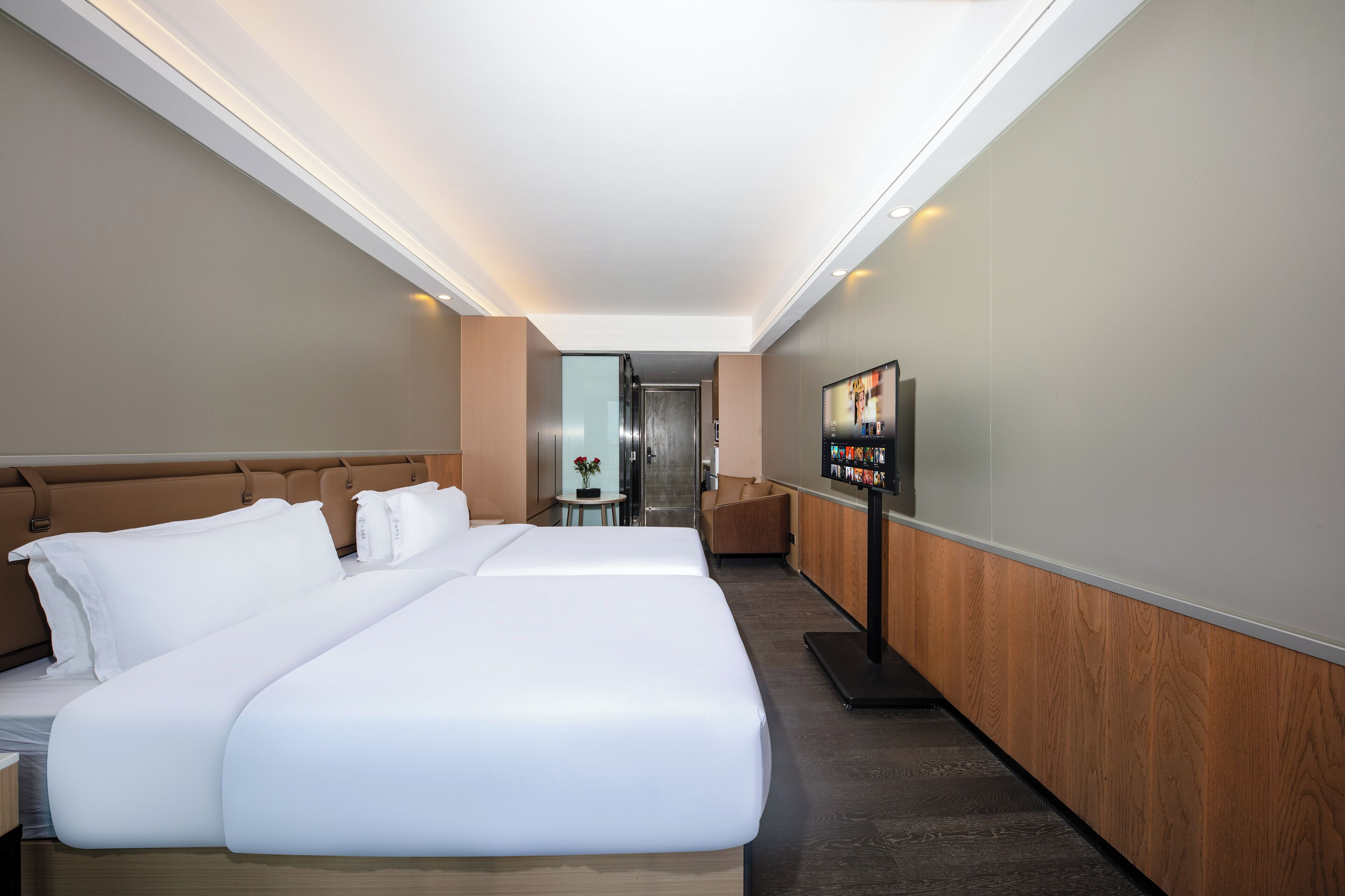 Een hotelkamer met een groot bed, een televisie en een klein tafeltje met een bloevas.