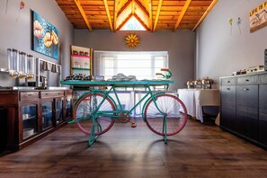 A kitchen with a teal bicycle, wooden cabinets, and a sun decoration on the ceiling. - BluSalzz Collection Suvaasa - Ramgarh (Ramgarh)