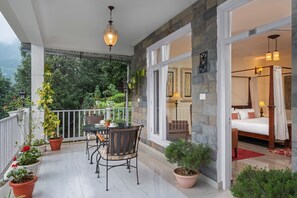 A balcony with a table and chairs, potted plants, and a view of the surrounding greenery. - BluSalzz Collection Suvaasa - Ramgarh (Ramgarh)