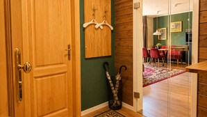 A wooden door with a brass handle, a coat rack with a decorative item, and a pair of umbrellas leaning against the wall. - Parkside Retreat Central location perfect for couples and families (Bad Muskau)