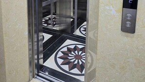 An elevator with a metallic interior, glass doors, and a digital control panel on the wall. - Heart Home (Hanoi)