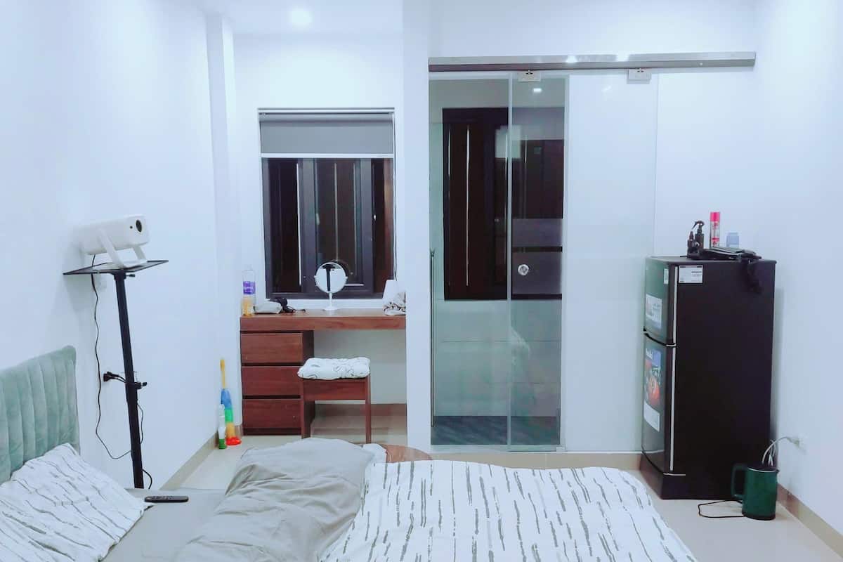 A bedroom with a bed, a desk, a wardrobe, and a mirror.