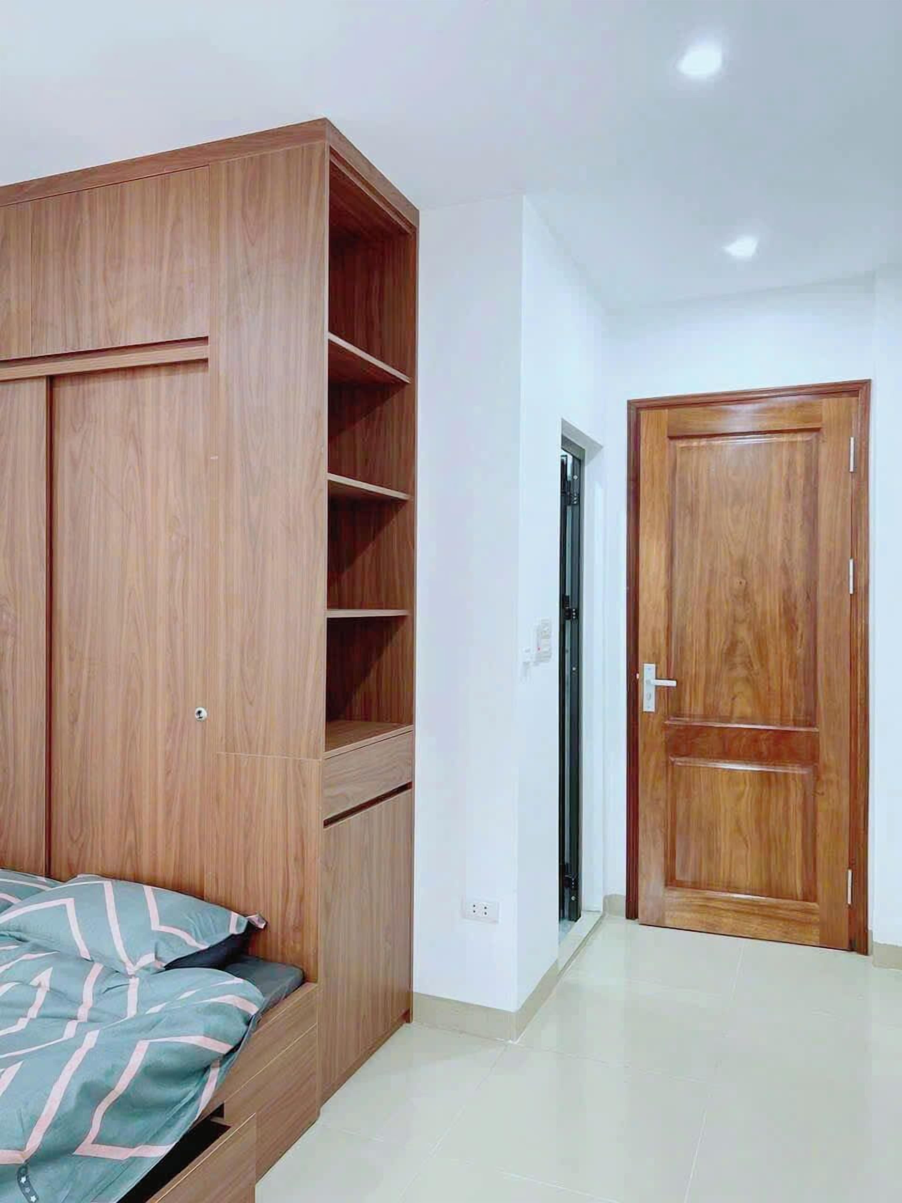 Une chambre avec une armoire en bois, un lit avec une literie à motifs et une porte.