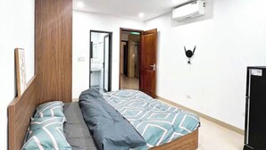 A modern bedroom with a wooden bed frame, a large mirror, and an air conditioning unit on the wall. - Heart Home (Hanoi)