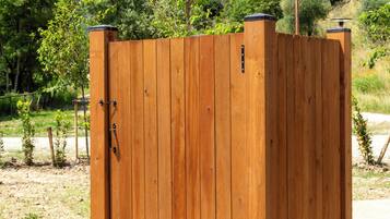 Eine hölzerne Sauna im Freien mit einem Metall-Dach und einer Holzterrasse.