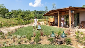 A rustic wooden building with a covered patio and a garden in front. -  Palagina Il Borgo Agricolo (Figline e Incisa Valdarno)