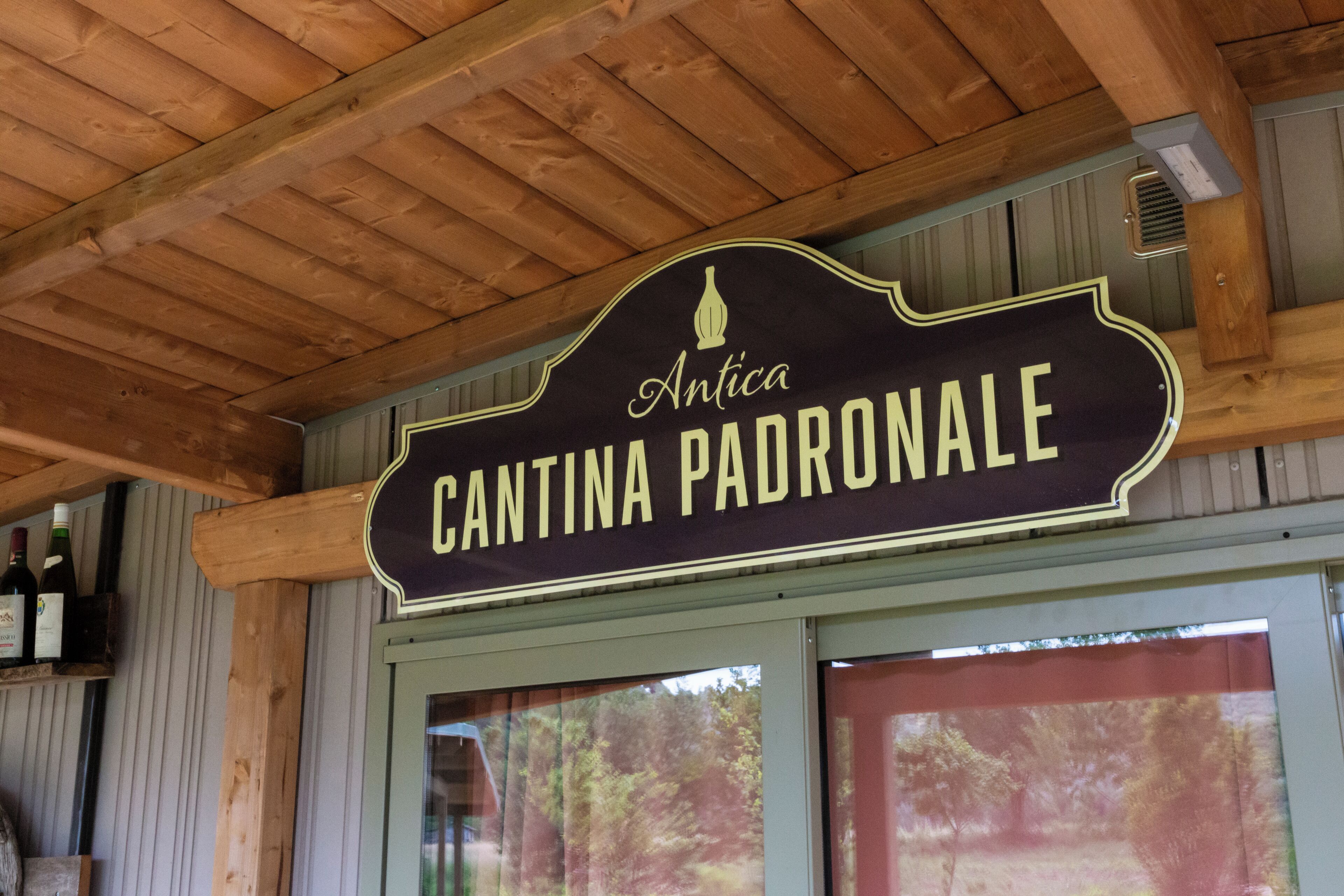 A wooden ceiling with a sign that reads "Antica Cantina Padronale."