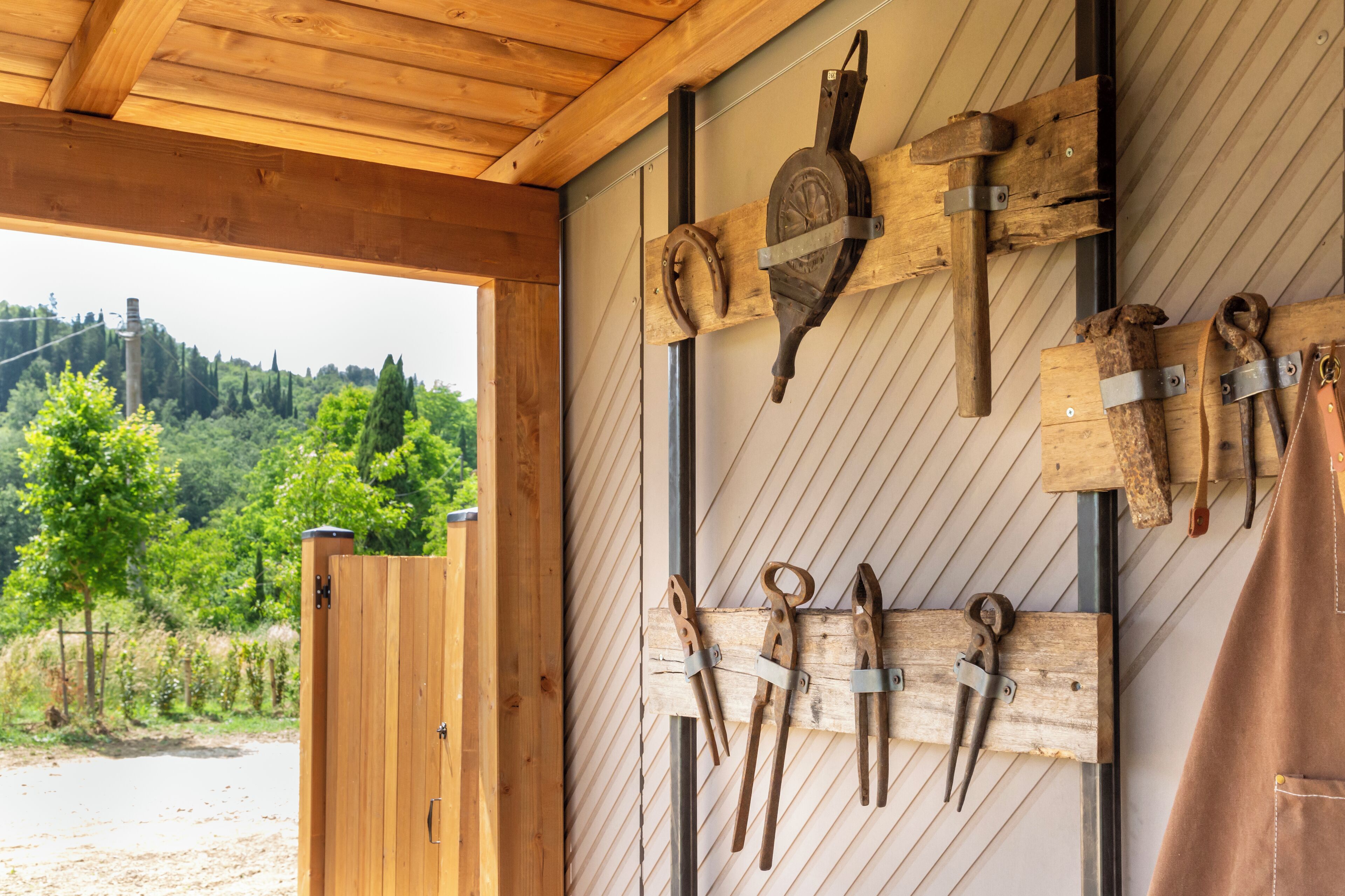 A rustic wooden interior with a wooden door and a wall-mounted tool rack.