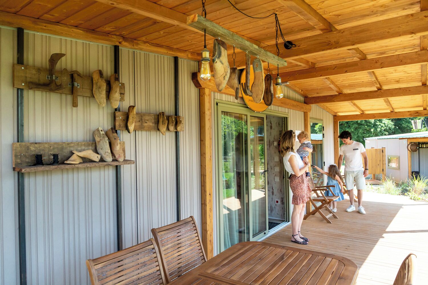 A covered outdoor area with wooden furniture, a glass door, and a wooden shelf with boots.