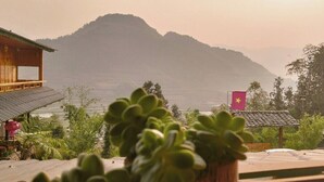 A building with a view of a mountain and a flag. - Lý Gia Homestay (Quan Ba)