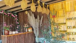 A rustic interior with wooden walls, a shelf with flowers, a Christmas tree, and hanging lights. - Lý Gia Homestay (Quan Ba)