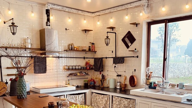 Una cocina moderna con armarios blancos, una isla de madera y un ventanal con vistas al exterior.