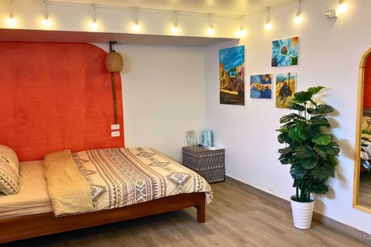 Ein Schlafzimmer mit einem Bett, einer Zimmerpflanze und Wandbildern.