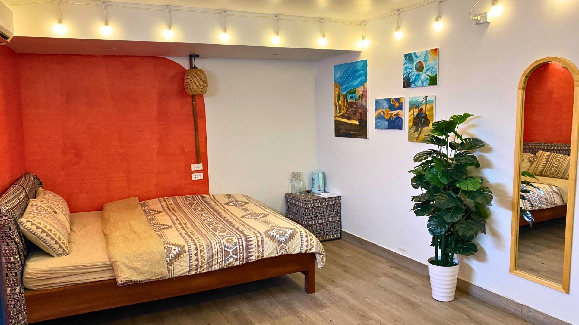 A bedroom with a wooden bed, a large mirror, and a potted plant.
