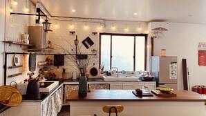 Una cocina moderna con una isla central, iluminación colgante y vistas de la ciudad a través de amplios ventanales.