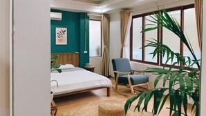 Un dormitorio con cama, una silla, una ventana y una planta.