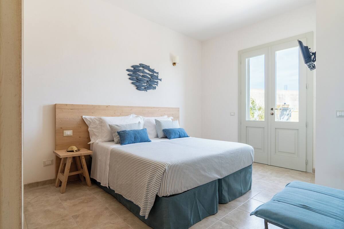 A bedroom with a bed, bedside table, and a wall decoration.