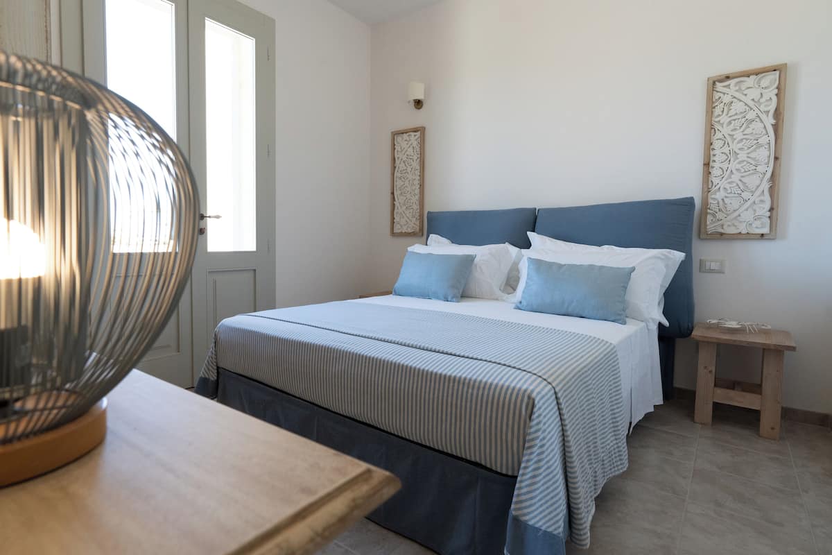 A bedroom with a bed, bedside tables, a lamp, and artwork on the walls.