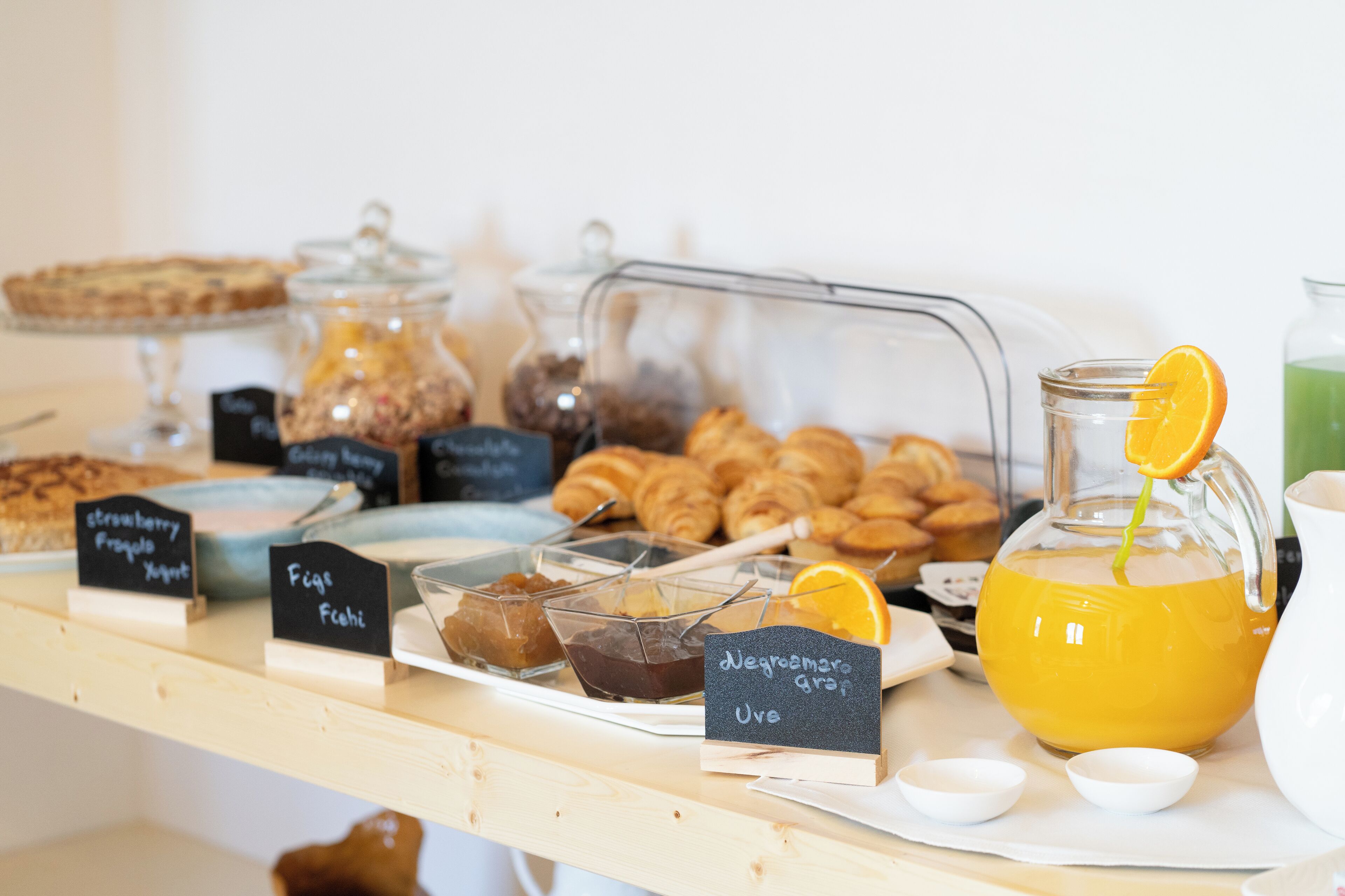 Un buffet per la colazione con diversi cibi e un boccale di succo d'arancia.
