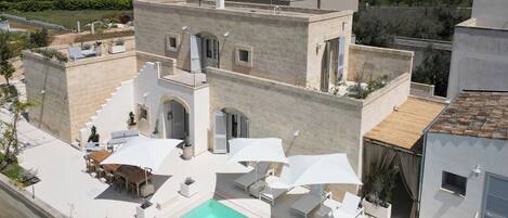 A modern villa with a rooftop pool, outdoor seating, and a view of the surrounding landscape.