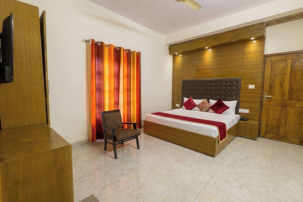 A bedroom with a bed, a chair, a wooden wardrobe, and a curtain.