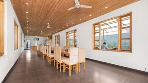 A spacious dining area with wooden ceiling and large windows, providing a view of the outdoors.