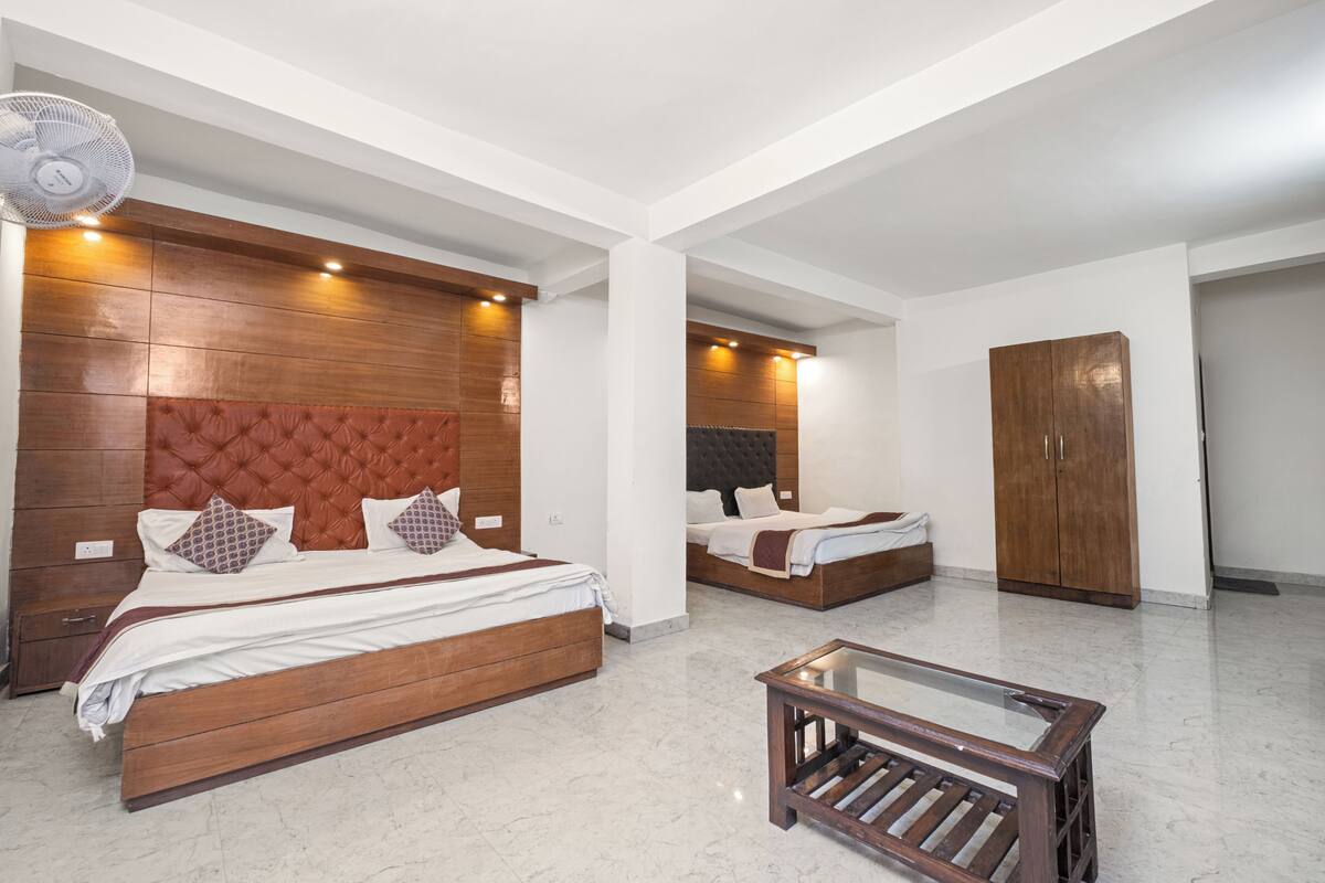 A hotel room with two beds, a wooden headboard, a glass coffee table, and a large wardrobe.